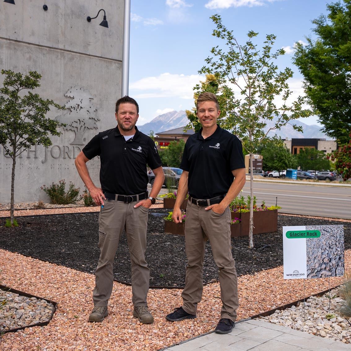 two water conservation officers in black shirts and brown pants stand in front of public works